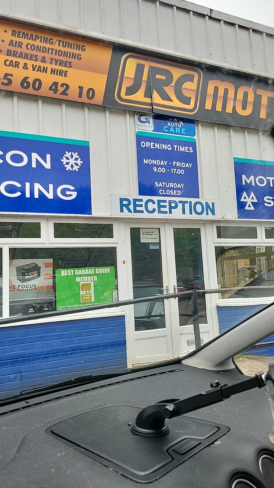 The JRC Motors reception entrance with the service board and opening times sign