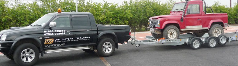 The JRC Motors recovery pickup towing a Land Rover on a trailer